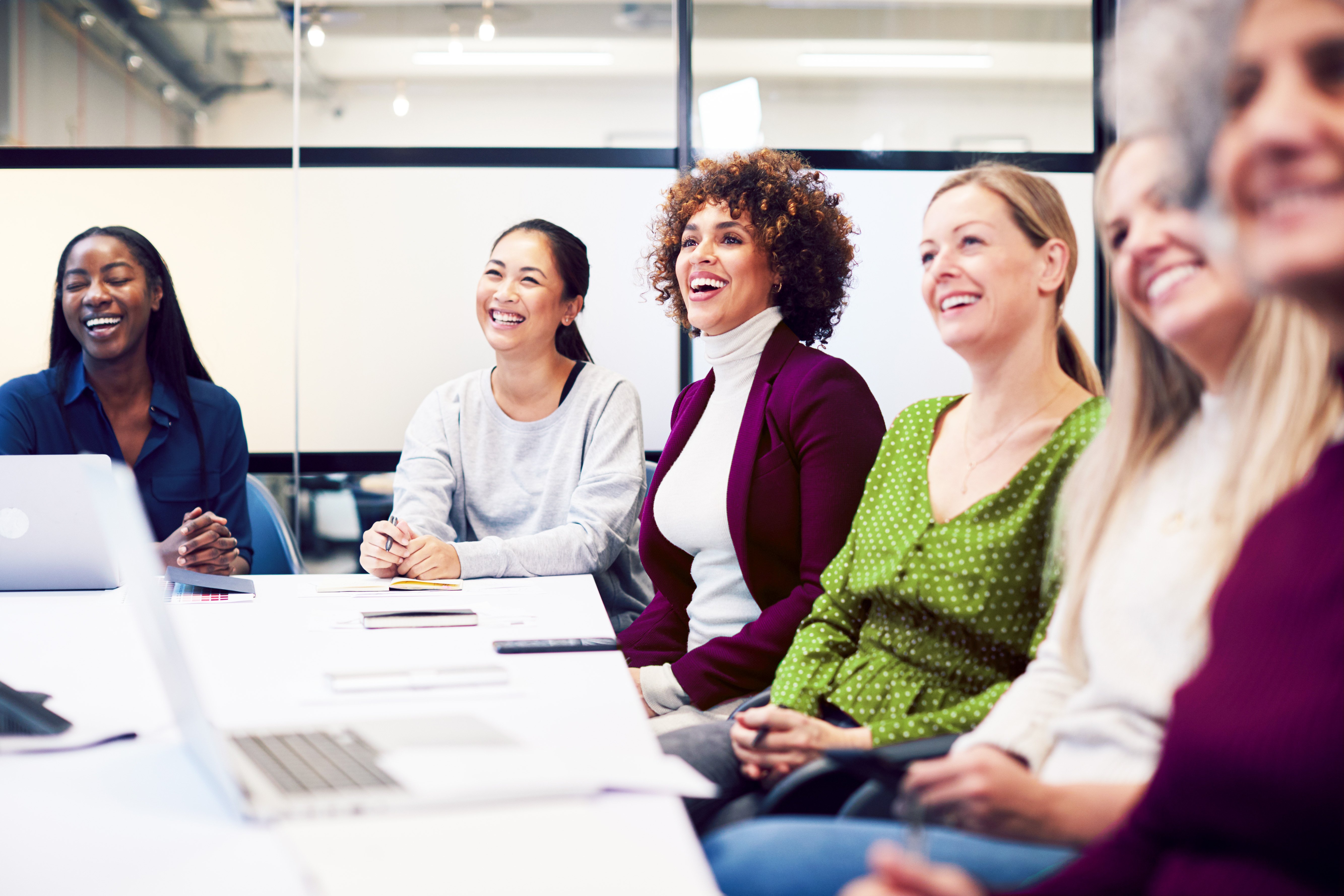 Line Of Businesswomen In Modern Office Listening To Presentation By Colleague